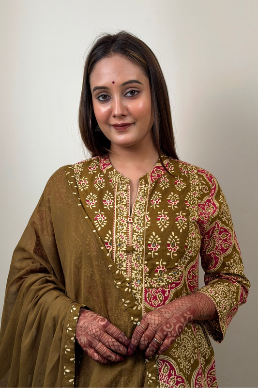 Woman wearing a traditional embroidered dress against a plain background