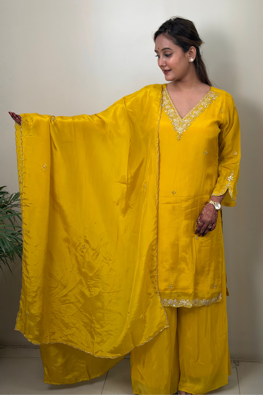 Woman wearing a yellow traditional outfit with a plain background