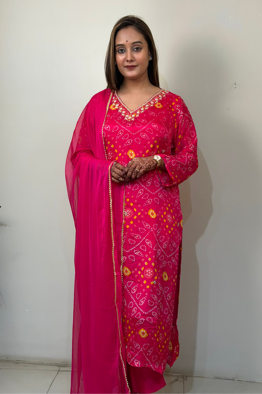 Woman wearing a pink traditional outfit with floral patterns against a white wall.