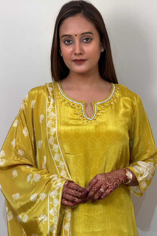 Woman wearing a yellow traditional outfit with white patterns on a plain background